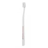 Szczoteczka do zębów SWISSDENT Profi Gentle Extra Soft w oryginalnym przezroczystym opakowaniu, ultramiękkie włosie i smukła biała rękojeść, widok produktu z przodu.